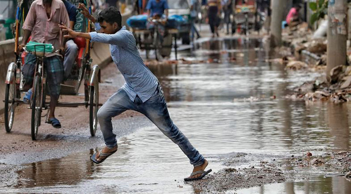 A pedestrian jumps over a puddle in Chankharpul, Dhaka. Rainwater causing sufferings on Dhaka roads during monsoon, a common scene in Dhaka. Dipu Malakar clicked the moment on 22 July.