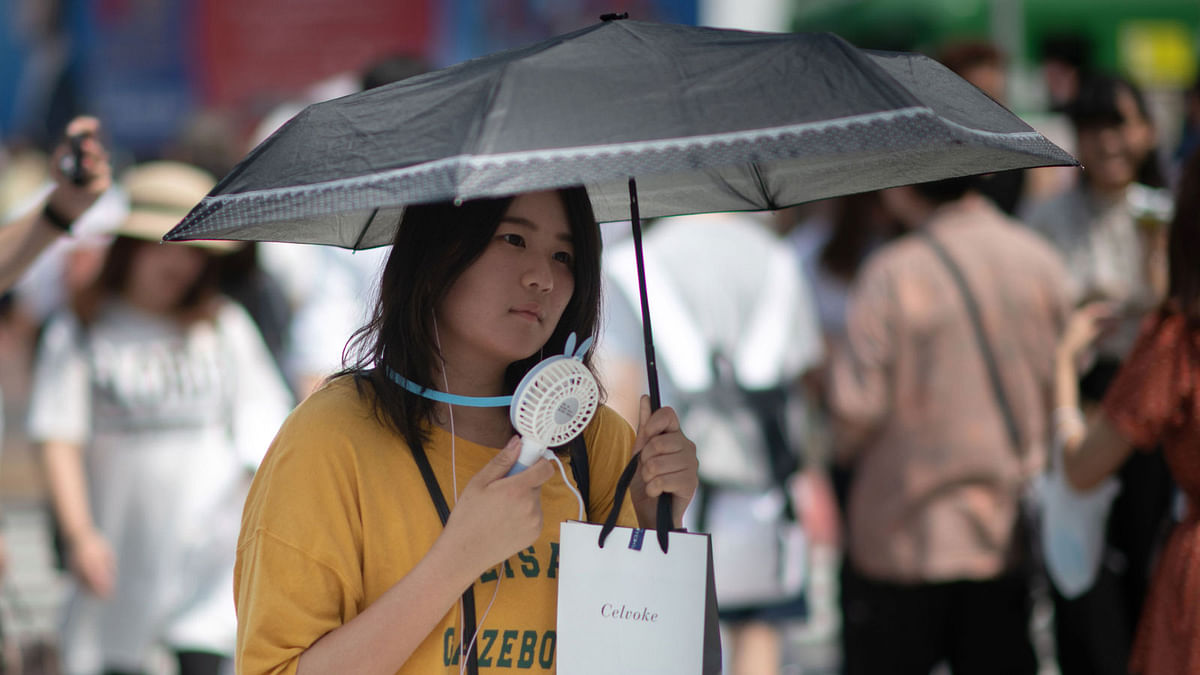 A woman uses a portable fan to cool herself in Tokyo on 24 July 2018, as Japan suffers from a heatwave. Photo: AFP