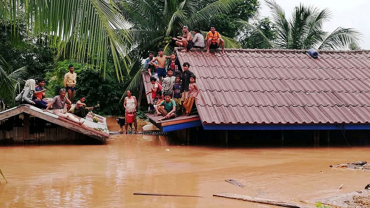 Residents cross flooded areas of Sanamxai, Attapeu province on 25 July 2018. The Laotian prime minister said on 25 July that 131 people are still missing two days after a dam collapse swamped several villages in the country`s south, killing at least 26 people. Photo: AFP