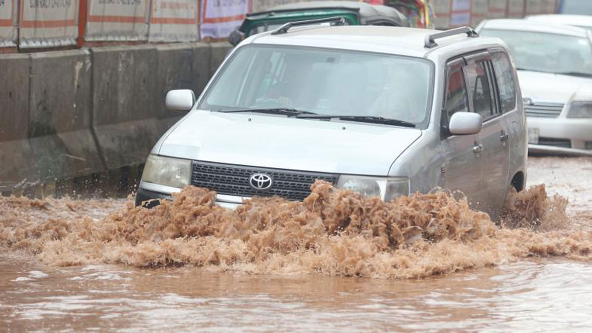 A car is stuck on the waterlogged Begum Rokeya Sarani in Kazipara, Mirpur, Dhaka on 25 July. The road full of potholes is now submerged by rainwater. Photo: Abdus Salam.