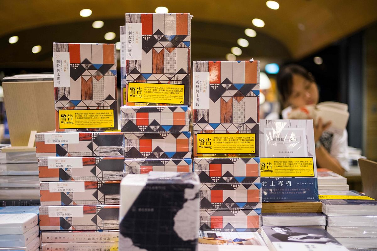 Copies of Japanese writer Haruki Murakami`s latest novel `Killing Commendatore` are displayed sealed in wrappers with yellow warning notices in a bookstore in Hong Kong on 26 July 2018. AFP