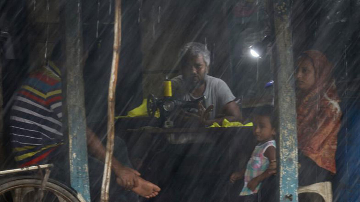 A man and a woman are gossiping in a tailor shop in Kachua, Bagerhat on 25 July. The incessant rains have trapped the duo in the shop. Photo: Saddam Hossain