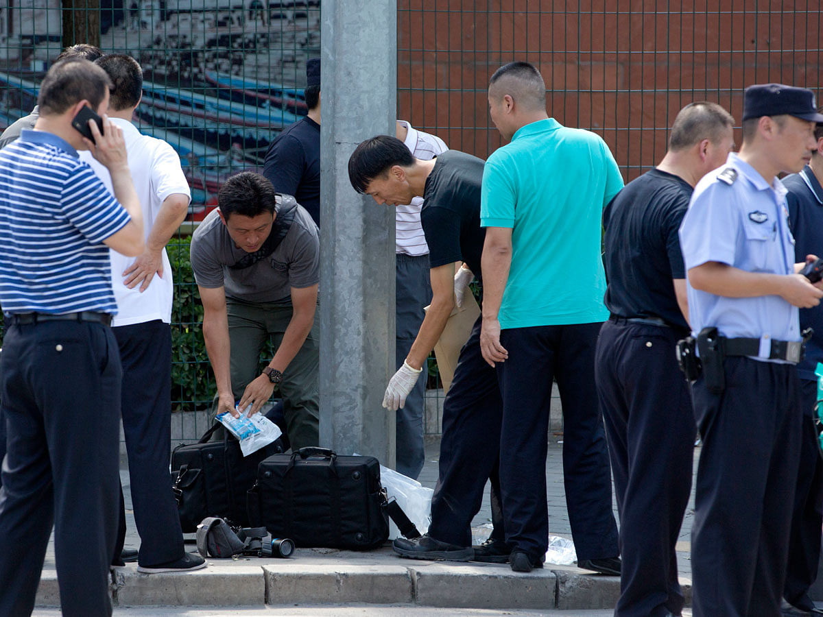 Chinese officials work near the site of a reported blast just south of the U.S. Embassy in Beijing, Thursday, 26 July 2018. Photo: AP  Meta: A man exploded a small homemade bomb outside the US embassy in Beijing on Thursday, injuring only himself, according to police and an embassy spokesperson.