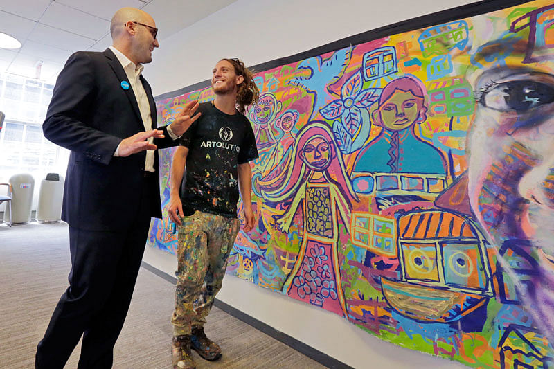 In this 20 June, photo, vice president of marketing and communications for UNICEF USA Francesco De Flaviis, left, talks with co-founder Max Levi Frieder, of Denver, beside a mural created by Rohingya refugees that`s displayed at the offices of UNICEF USA, in New York. Photo: AP