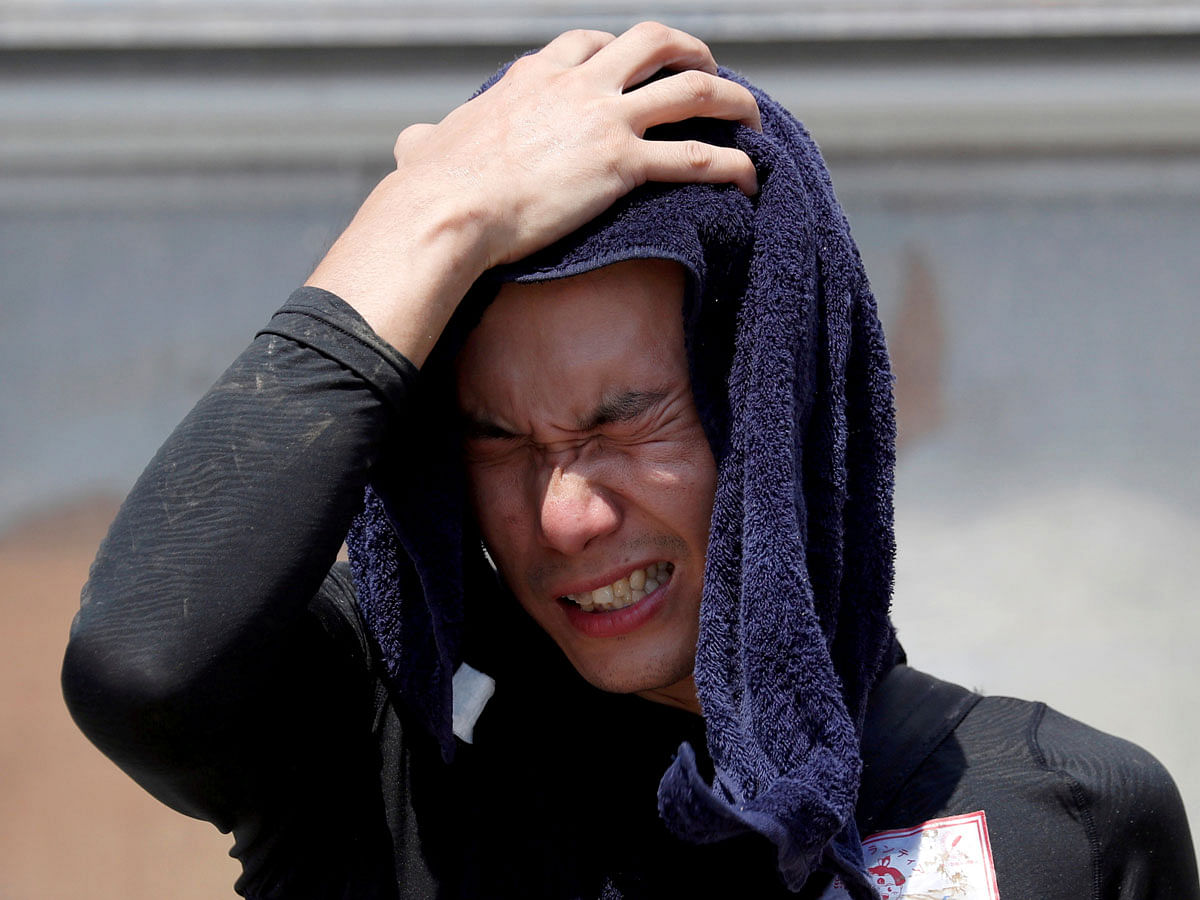 A volunteer, for recovery work, wipes his sweat as he takes a break in a heat wave at a flood affected area in Kurashiki. Reuters