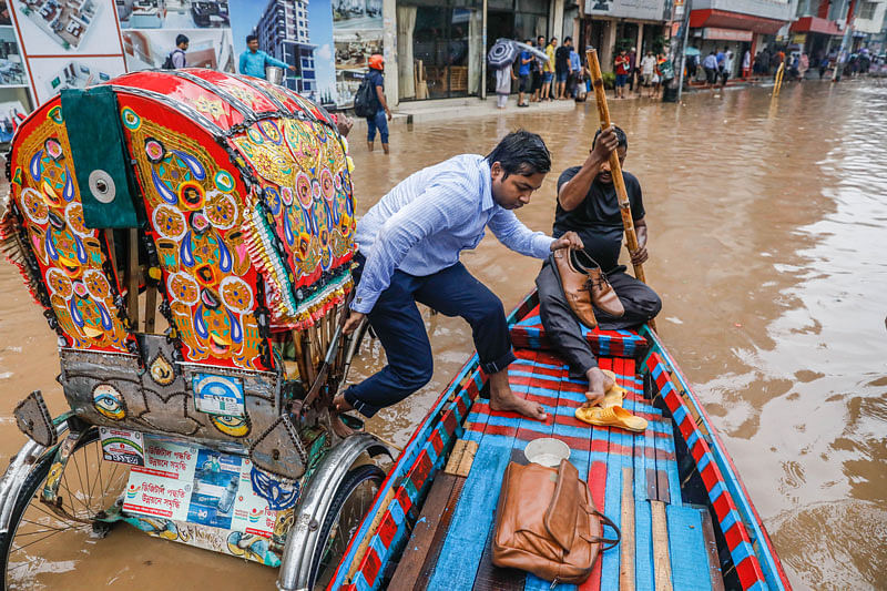 Rainwater inundates the roads. A man leaves rickshaw for boat as he realises he would get wet if he continues with the rickshaw in Kazipara of Dhaka on 23 July. Photo: Dipu Malakar