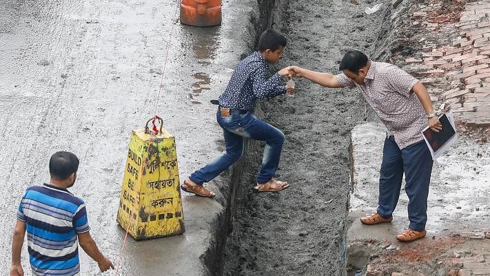 A man helps a boy cross a ditch on Topkhana Road, Dhaka. Pedestrians in the area suffer due to the trench dug for development works. The picture was taken by Dipu Malakar on 27 July.