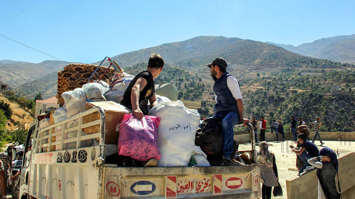 Syrian refugees sit with their packed belongings as they prepare to be evacuated from the southern Lebanese village of Shebaa on 28 July to return back to Syria. Photo: AFP