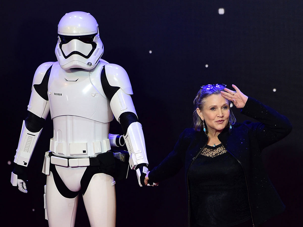 In this file photo taken on 16 December, 2015 US actress Carrie Fisher ® poses with a storm trooper as she attends the opening of the European Premiere of “Star Wars: The Force Awakens” in central London. Photo: AFP