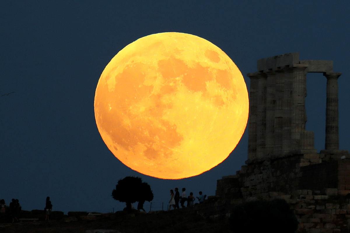 People watch a full moon rising behind the Temple of Poseidon before a lunar eclipse in Cape Sounion, near Athens, Greece, on 27 July 2018. Photo: Reuters