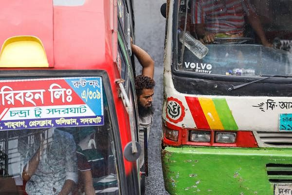 A bus conductor is standing at the gate risking his life while another bus is so close. Accidents frequently occur due to unhealthy competitions among the public bus drivers in Dhaka. The picture was taken by Dipu Malakar from Paltan, Dhaka on 27 July.