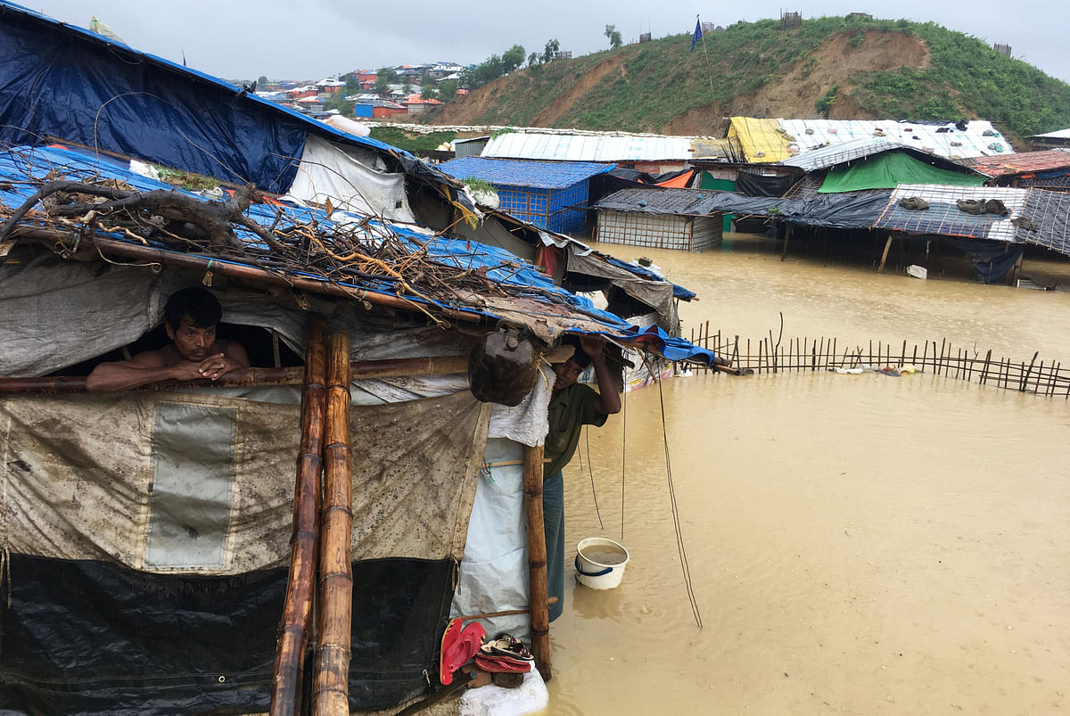 Abdul Hakim (L), a Rohingya refugee man looks on as his shelter gets flooded after heavy rain in Cox’s Bazar, Bangladesh on 25 July 2018. Photo: Reuters