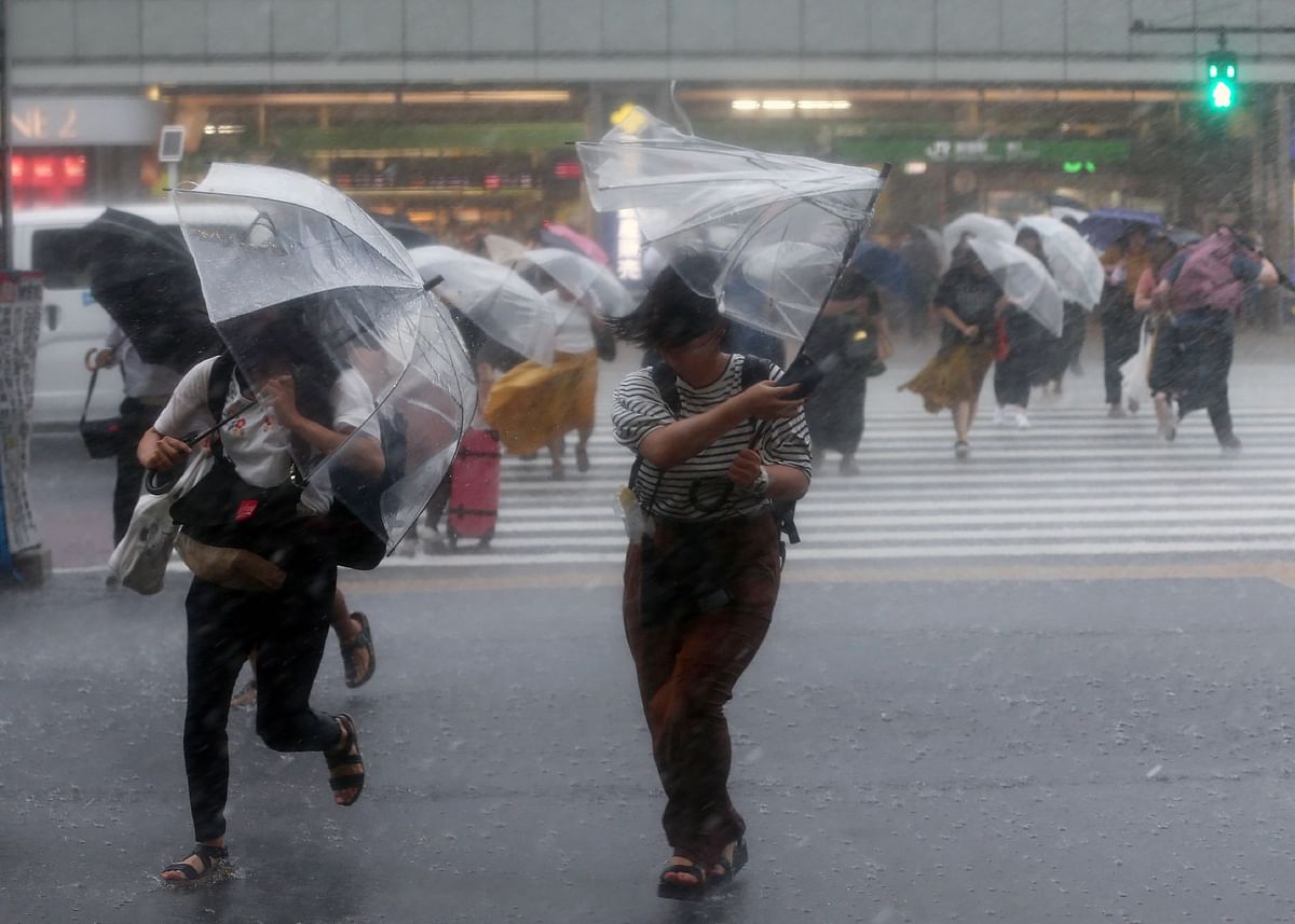 In this photo taken on July 28, 2018, people protect themselves with umbrellas as heavy rains caused by Typhoon Jongdari fall in Tokyo. A powerful storm slammed into central Japan on July 29, bringing heavy rains as it churned across western areas already devastated by floods and landslides. AFP
