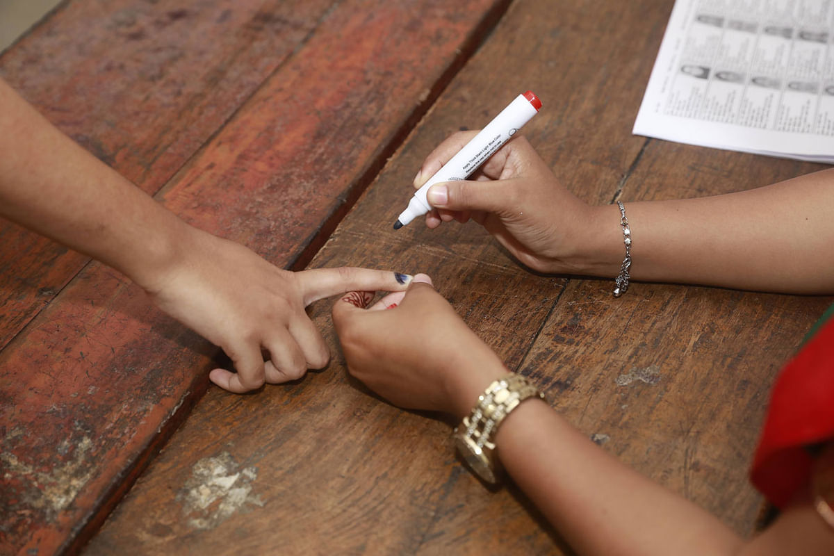 An election officer marks a voter’s hand with indelible ink at Hatem Ali primary school polling station of ward no. 20 in Sadipur of Sylhet city on 30 July. Photo: Suvra Kanti Das