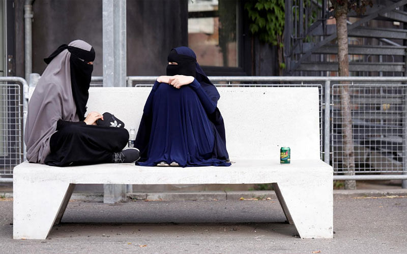 Sabina (L), 21, and Alaa, both students and wearers of the niqab, sit in a park in Copenhagen, Denmark, on 17 July 2018. -- Reuters