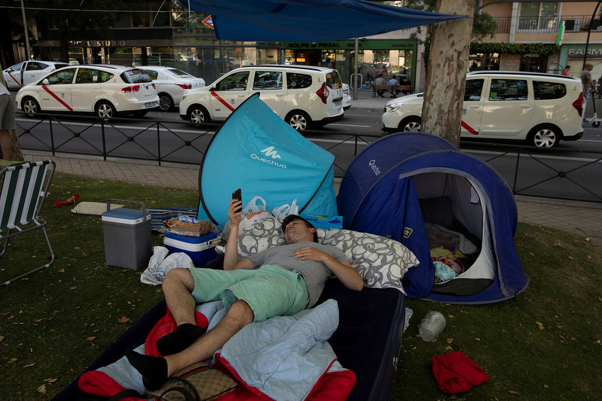 A taxi driver rests on an air mattress as taxis block a section of the main avenue Paseo de la Castellana during an indefinite strike against what they say is unfair competition from ride-hailing and car-sharing services such as Uber and Cabify in Madrid, Spain, 1 August 2018. Photo: Reuters