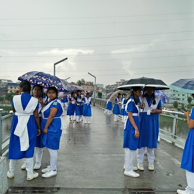 Students with umbrellas in a light rain on the overbridge in Hatirjheel, Dhaka on Tuesday. Photo: Nusrat Nowrin