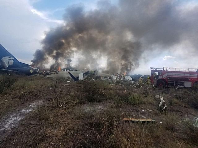 Firefighters douse a fire as smoke billows above the site where an Aeromexico-operated Embraer passenger jet crashed in Mexico`s northern state of Durango on 31 July 2018, in this picture obtained from social media. Photo: Reuters