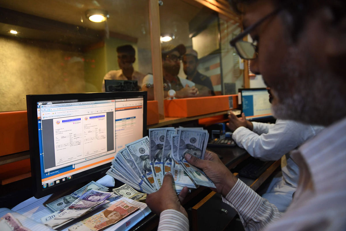 A Pakistani currency dealer counts USD banknotes at a currency exchange shop in Karachi on 1 August 2018. Pakistan`s next government faces growing fears of a balance of payments crisis, with speculation mounting it will have to seek its second bailout in five years from the International Monetary Fund. -- AFP