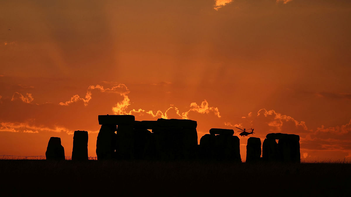 A helicopter flies behind the Stonehenge stone circle during sunset in southwest Britain on 26 July. Photo: Reuters