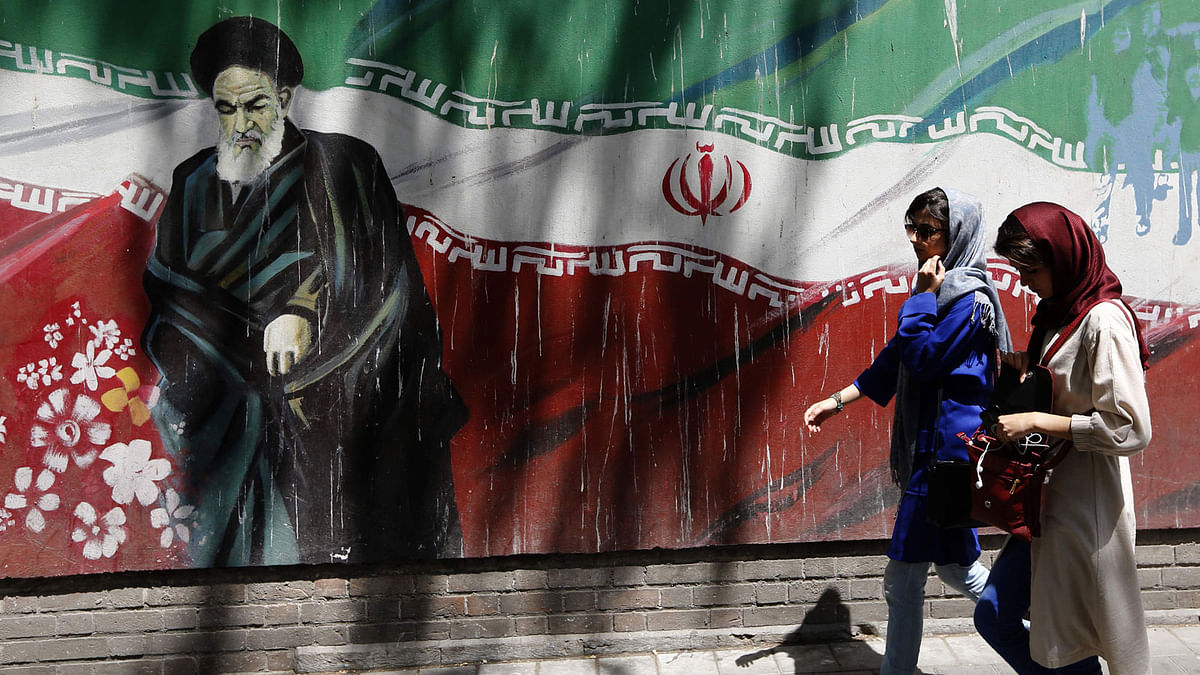 Iranians walk by mural painting of the founder of the Islamic Republic Ayatollah Ruhollah Khomeini on the wall of the former US embassy in the Iranian capital Tehran on 7 August 2018. Photo: AFP
