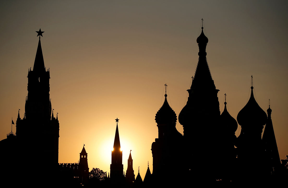 The sun sets behind the Kremlin`s Spasskaya Tower and St. Basil`s Cathedral in Moscow. Photo: Reuters