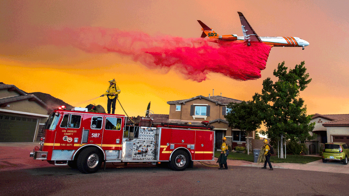 A plane drops fire retardant behind homes along McVicker Canyon Park Road in Lake Elsinore, Calif., as the Holy Fire burned near homes on 8 August. Photo: AP