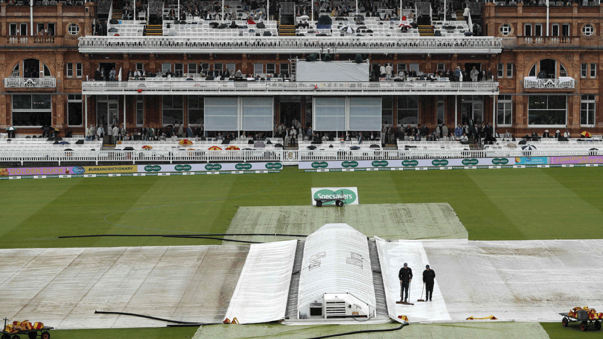 Ground staff sweep rainwater off the covers as rain delays start of play on the first day of the second Test cricket match between England and India at Lord`s Cricket Ground in London on 9 August 2018. Photo: AFP