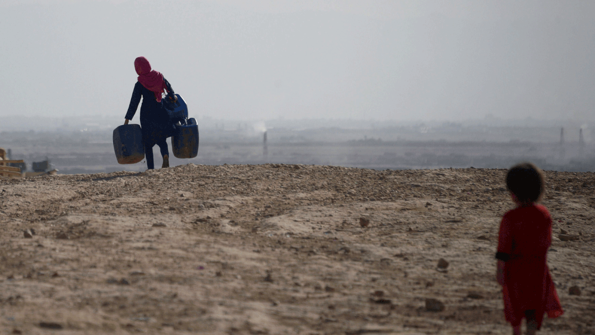 This file photo taken on 19 July 2018 shows an Afghan girl (L) carrying empty containers to collect water, as a child looks on, in Sakhi village on the outskirts of Mazar-i-Sharif. A 70 per cent shortfall in snow and rain across most of Afghanistan in recent months decimated the winter harvest, threatening the already precarious livelihoods of millions of farmers and sparking warnings of severe food shortages, as Afghanistan`s worst drought in decades ravages the war-torn country. -- AFP
