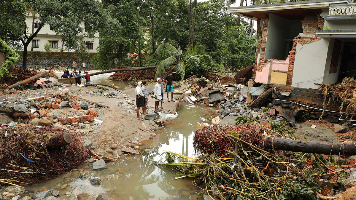 In this file photo taken on 10 August 2018 Indian residents look at houses destroyed by flood waters at Kannappankundu in Kozhikode, in the Indian state of Kerala on 10 August 2018. A family in the flood-ravaged Indian state of Kerala narrowly escaped death after their pet dog woke them up minutes before a landslide destroyed their home, local media reported on 13 August. Flash floods triggered by the annual monsoon rains have pounded the tourist hotspot in the past few days, killing 39 people and leaving some 100,000 people homeless so far. -- AFP
