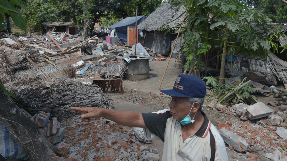 A man gestures next to damaged houses after an earthquake hit the area of Gangga on 12 August 2018. Photo: AFP