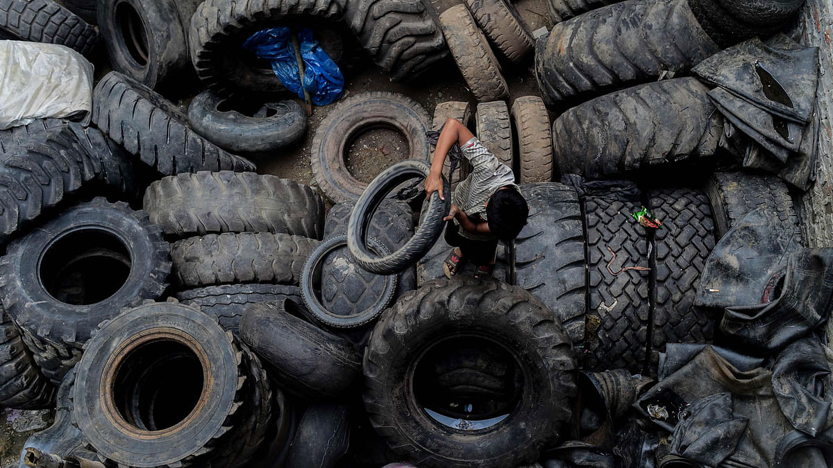 A Bangladeshi boy collects used tyres from piles of tyres in Dhaka on 13 August, 2018. Photo: AFP