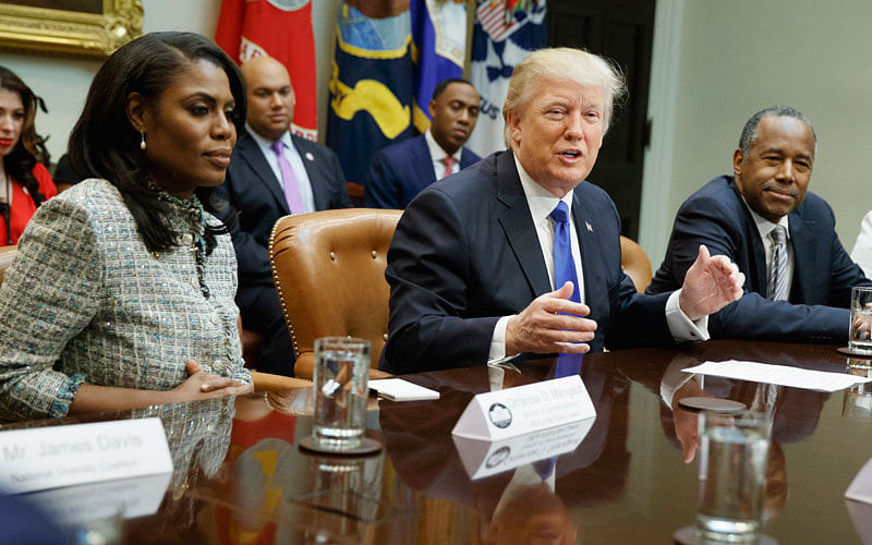 US president Donald Trump, centre, is flanked by White House staffer Omarosa Manigault Newman, left, and then-Housing and Urban Development secretary-designate Ben Carson as he speaks during a meeting on African American History Month in the Roosevelt Room of the White House in Washington. Photo: AP