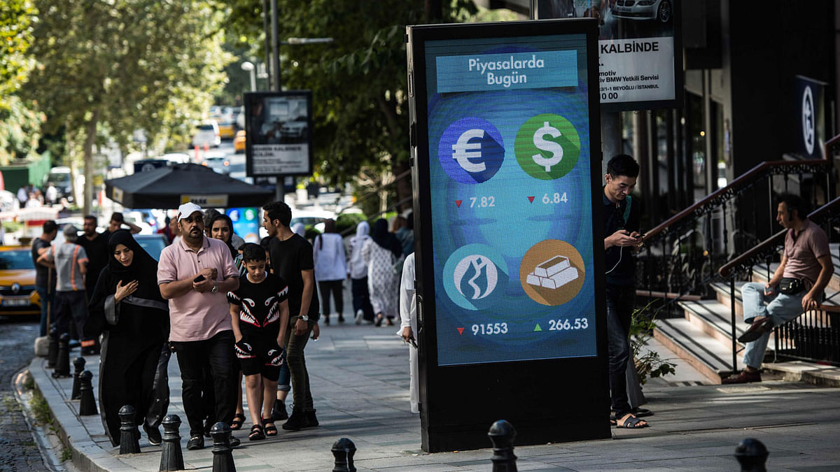 People walk past a digital billboard giving updates on various currencies and the Turkish stock exchange in Istanbul on 13 August 2018. Photo: AFP