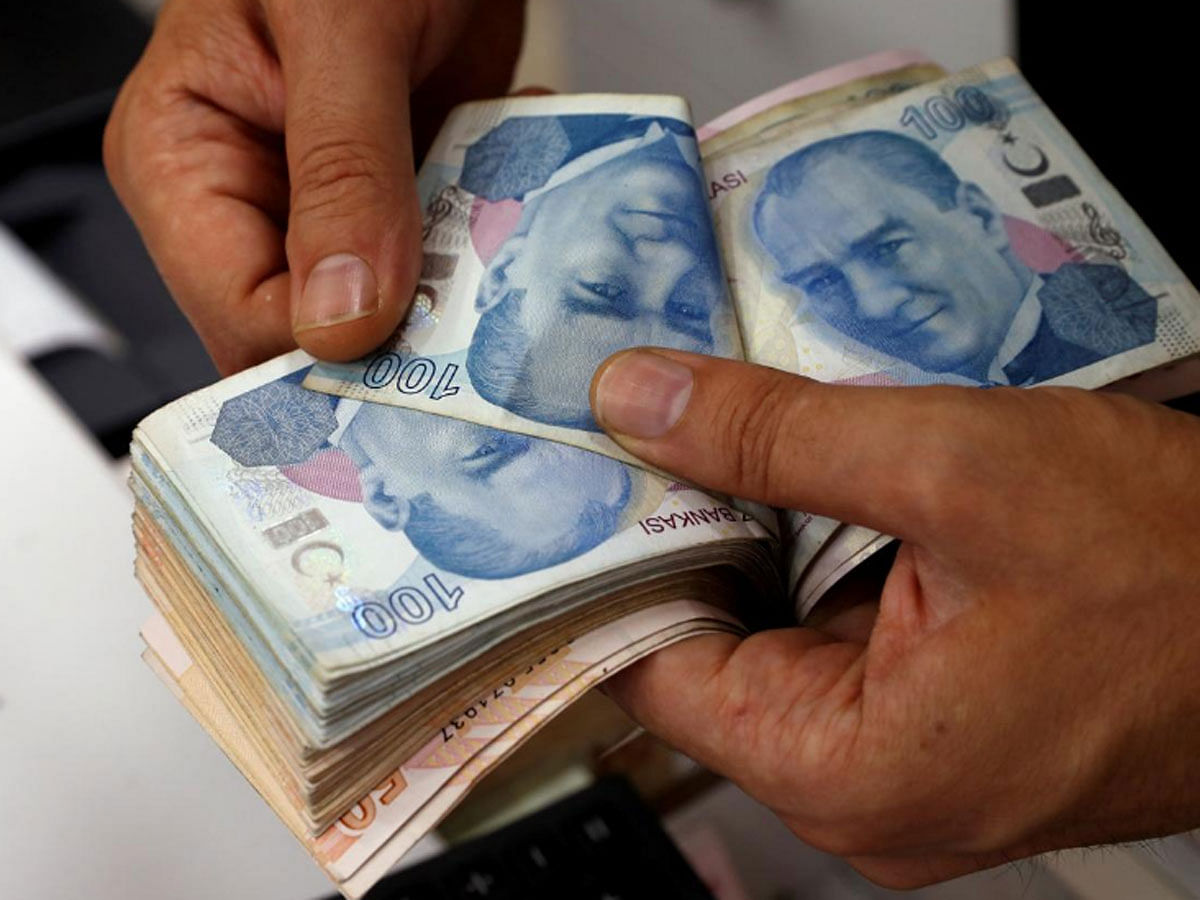 A money changer counts Turkish lira banknotes at a currency exchange office in Istanbul, Turkey 2 August 2018. -- Reuters