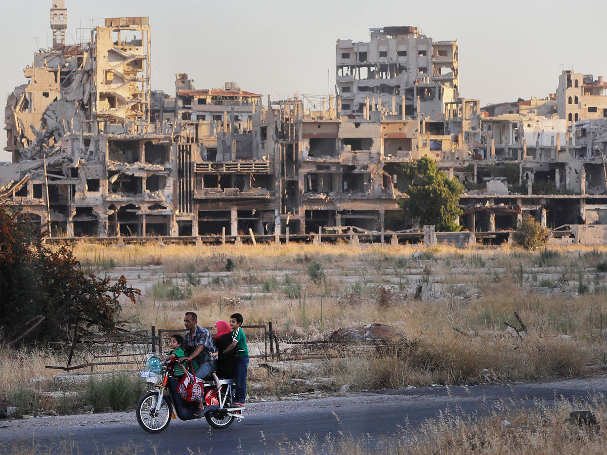 People ride their motorcycle by damaged buildings in the old town of Homs, Syria, Wednesday, 15 August 2018. The Russian defense ministry said Wednesday it is coordinating efforts to help Syrian refugees return home and rebuild the country`s infrastructure destroyed by the civil war. Photo: AP