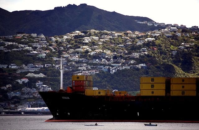 Houses can be seen on the hillside behind a rower and motor-boat as they pass a container ship as it sails into Oriental Bay in the New Zealand capital city of Wellington, New Zealand, 17 September 2011. Reuters