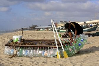 Palestinian fisherman Mouad Abu Zeid repairs his boat that he made of 700 Plastic empty bottles on a beach in Rafah in the southern Gaza Strip on 14 August 2018. Photo: AFP