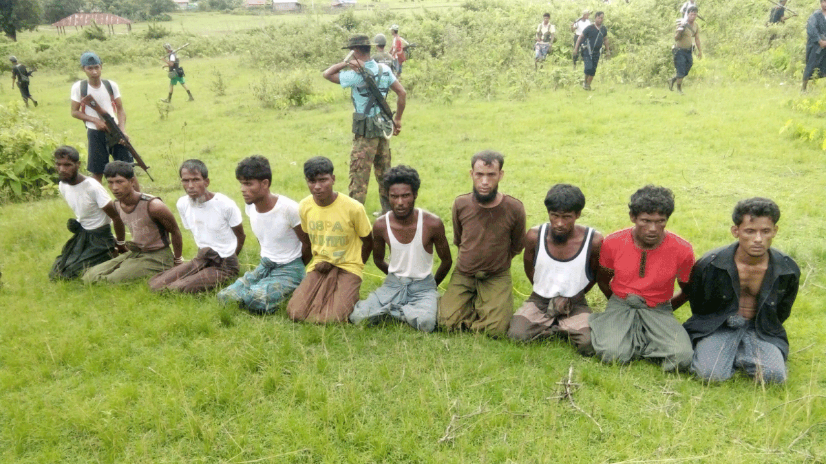 Rohingya Muslim men with their hands bound kneel as members of the Myanmar security forces stand guard in Inn Din village. Photo: Reuters