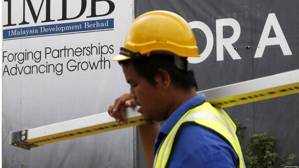 A construction worker walks past a 1Malaysia Development Berhad (1MDB) billboard at the Tun Razak Exchange development in Kuala Lumpur, Malaysia on 3 February 2016. -- Reuters