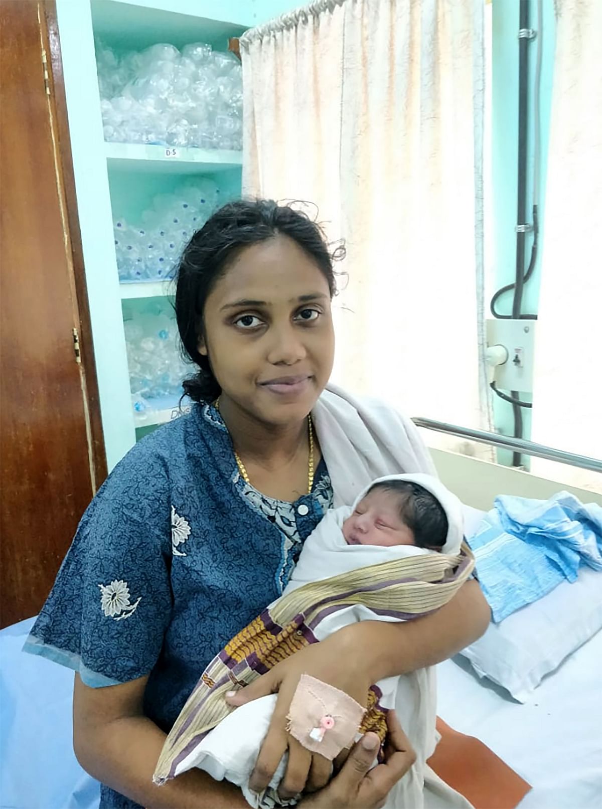 This handout photograph released by the Indian Navy on 18 August 2018 shows Sajita Jabeel, 25, with her newborn boy in a hospital in Kochi, after she was rescued while heavily pregnant from a roof in a flood affected area of Kochi in the southern state of Kerala. Photo: AFP