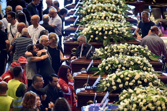 People mourn next to the coffins containing bodies of victims of the Genoa bridge collapse, at the Genoa Trade Fair and Exhibition Centre in Genoa, Italy on 18 August 2018. Photo: Reuters