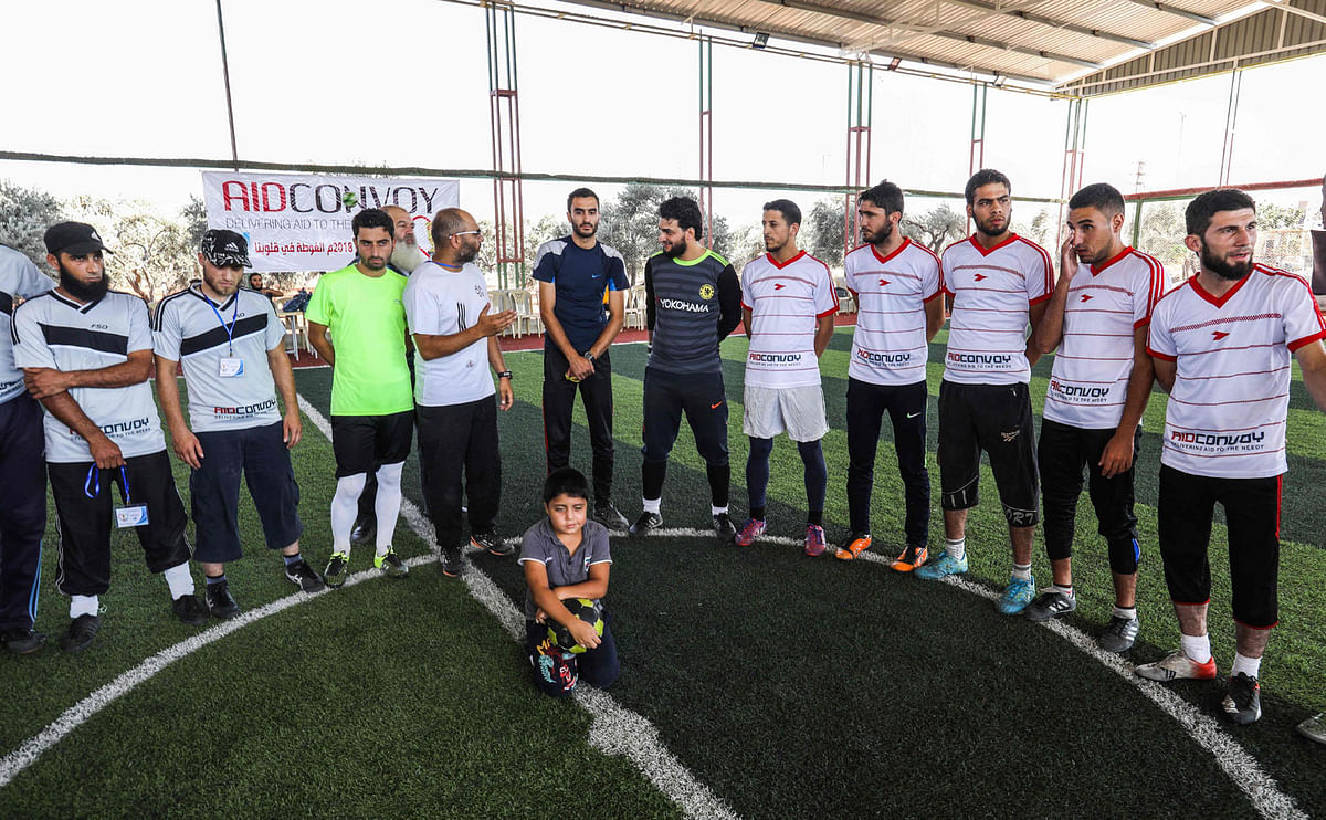 Syrian youths from Madaya in the Damascus countryside (gray with black stripe) and from Northern Syria (white with red stripes) line-up prior to the start of their match during a football tournament in the rebel-held northern Syrian city of Idlib on 7 August 2018. Photo: AFP