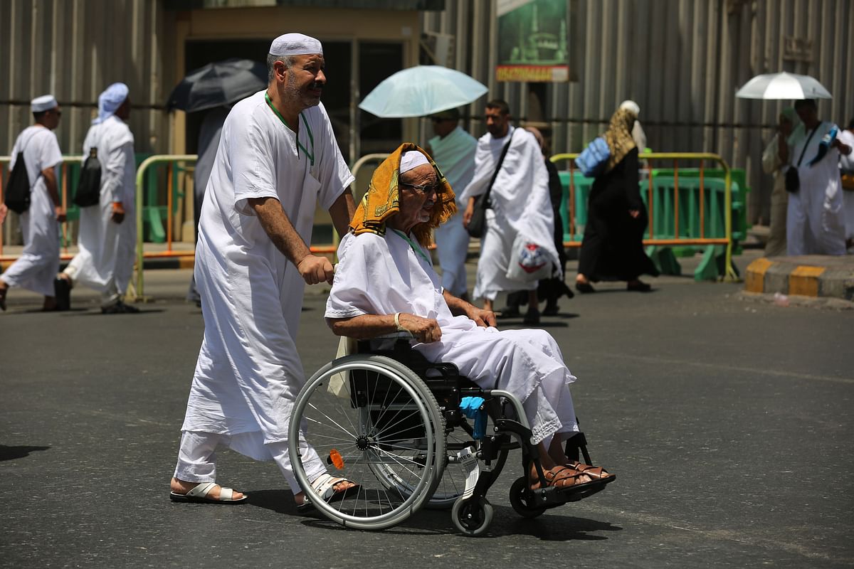 A man pushes the wheelchair of a fellow Muslim pilgrim in a street in Saudi Arabia`s holy city of Mecca on 18 August, 2018, ahead of the start of the annual Hajj pilgrimage. Photo: AFP