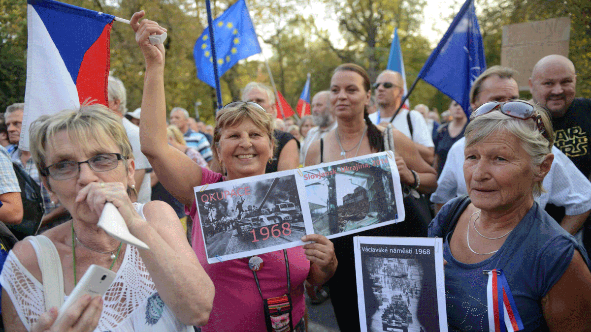 Women hold placards with photos from the Soviet-led invasion during a demonstration to commemorate the 50th anniversary of the Soviet-led invasion of former Czechoslovakia in 1968 in front of the Russian embassy on 20 August 2018 in Prague. -- Photo: AFP