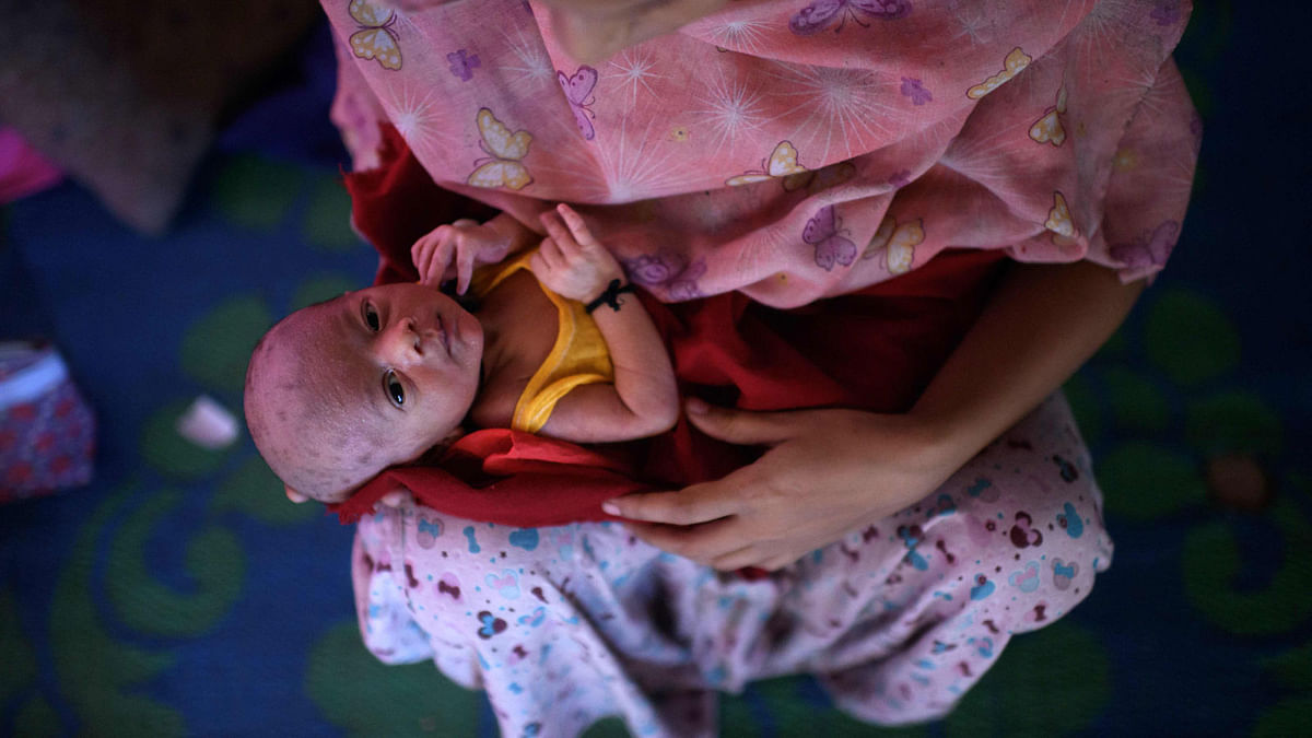 Rohingya refugee woman Johara Begum (21) holds her five-day-old baby boy Mohammad Anas, who was delivered with the help of a neighbouring midwife, in the shelter she shares with her husband and family at the Jamtoli refugee camp near Cox`s Bazar on 12 August 2018. -- AFP