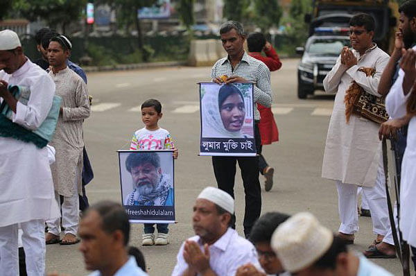 A man and a boy hold two placards on 22 August, 2018 at Jatiya Eidgah demanding release of renowned photographer Shahidul Alam and Eden Mohila College student Lutfunnahar Luma, arrested following recent demonstrations for safe roads. Photo: Hasan Raja