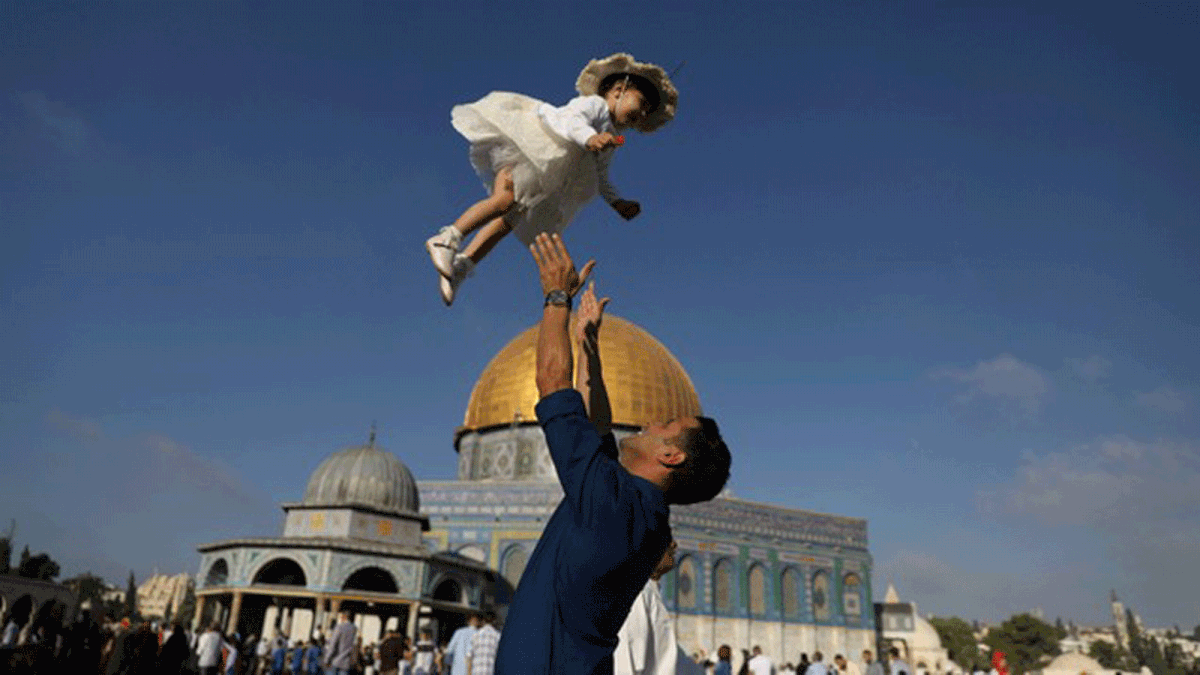 Palestinian man throws his child in the air following morning prayers marking the first day of Eid al-Adha celebrations, on the compound known to Muslims as al-Haram al-Sharif and to Jews as Temple Mount in Jerusalem`s Old City on 21 August 2018. Photo: Reuters