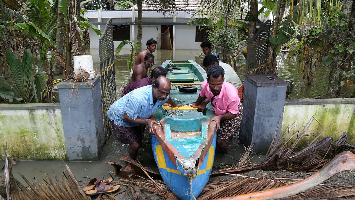 People push a boat through a gate of a flooded house at Kuttanad in Alleppey district in the southern state of Kerala, India on 24 August 2018. Photo: Reuters