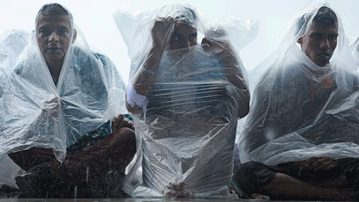 Travelling home for Eid on the roof of a train. They wrap themselves in plastic sheets in a futile attempt to ward off the rain. Chittagong railway station, 21 August. Photo: Jewel Shil